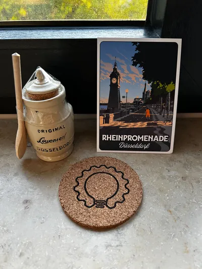 Düsseldorfer Löwensenf-Set und Postkarte „Rheinpromenade Düsseldorf“ als Speaker-Geschenk auf einer Fensterbank