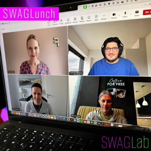 Vier Personen sind in einer Videokonferenz auf einem Laptopbildschirm zu sehen, angeordnet in einer 2×2-Kachelansicht. Alle sitzen jeweils vor unterschiedlichen Hintergründen in ihren Arbeits- oder Wohnräumen und schauen in die Kamera. Oben links ist eine Frau und ansonsten Männer, alle in legerer Kleidung zu sehen, teils mit Headset. Im Bild sind die Begriffe „SWAGLunch“ und „SWAGLab“ als grafische Overlays platziert. Der Fokus liegt auf dem digitalen Austausch in entspannter, kollegialer Atmosphäre.