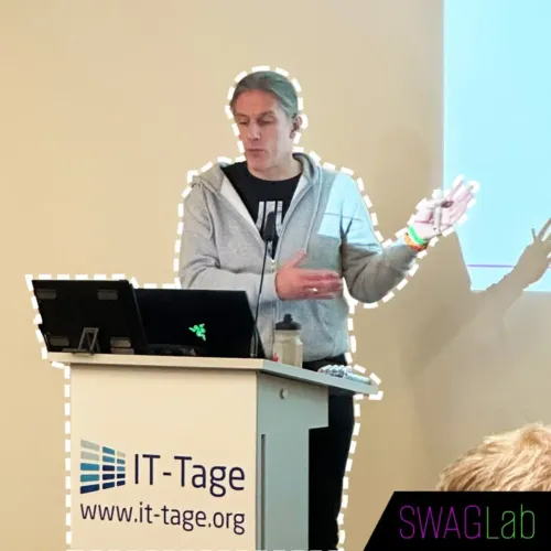 Eberhard Wolff hält einen Vortrag auf den IT-Tagen am Rednerpult mit Laptop und Präsentationsfolie im Hintergrund.